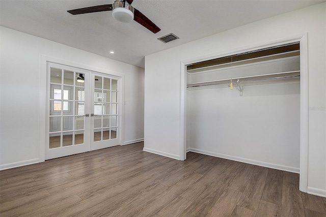 unfurnished bedroom featuring baseboards, visible vents, wood finished floors, french doors, and a closet