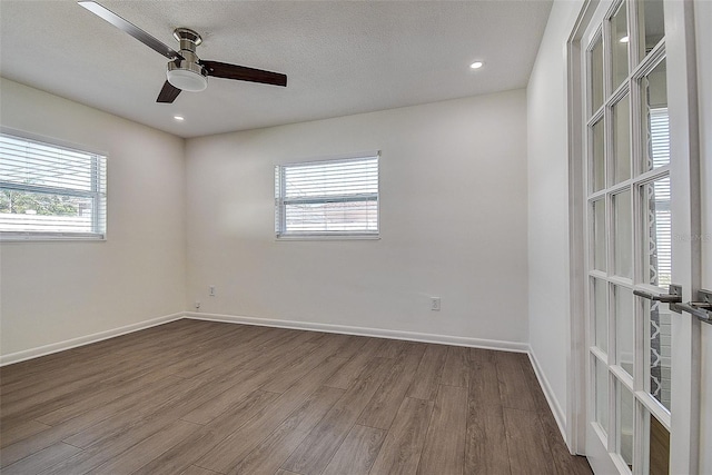 empty room featuring baseboards, a ceiling fan, dark wood-style floors, a textured ceiling, and recessed lighting