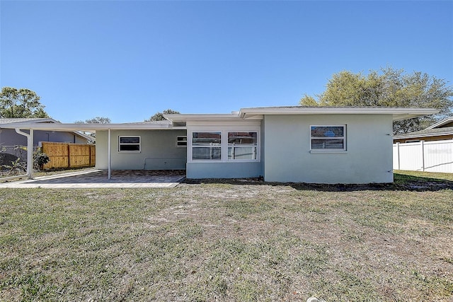 back of house with stucco siding, fence, a lawn, and a patio