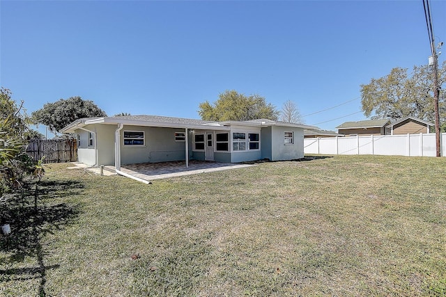 rear view of property featuring stucco siding, a fenced backyard, a lawn, and a patio