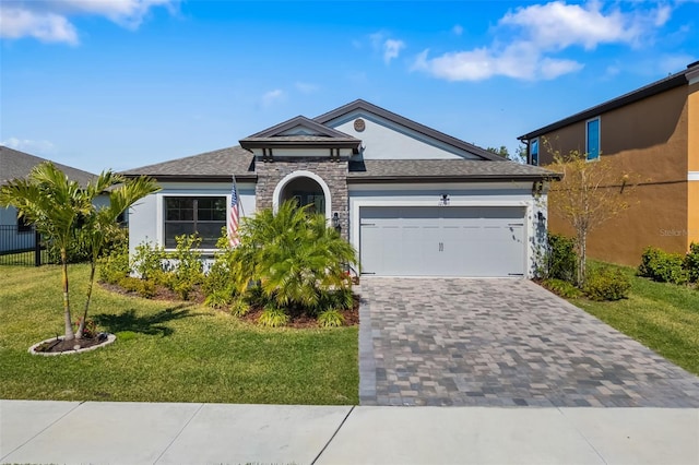 ranch-style house with decorative driveway, stucco siding, a garage, stone siding, and a front lawn