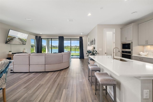 living room featuring light wood finished floors, visible vents, and recessed lighting