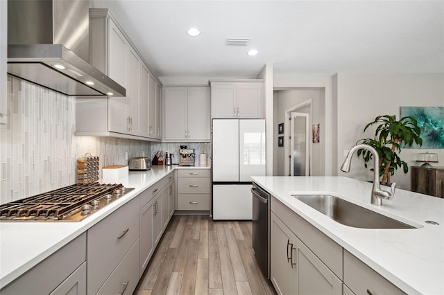 kitchen with visible vents, wall chimney exhaust hood, appliances with stainless steel finishes, gray cabinetry, and a sink