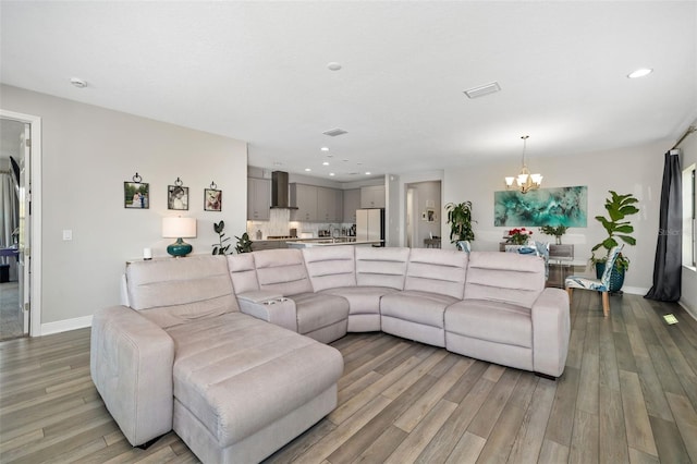 living area with recessed lighting, a notable chandelier, visible vents, baseboards, and light wood finished floors