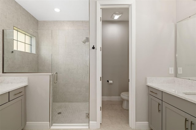 bathroom featuring toilet, a stall shower, vanity, tile patterned flooring, and baseboards