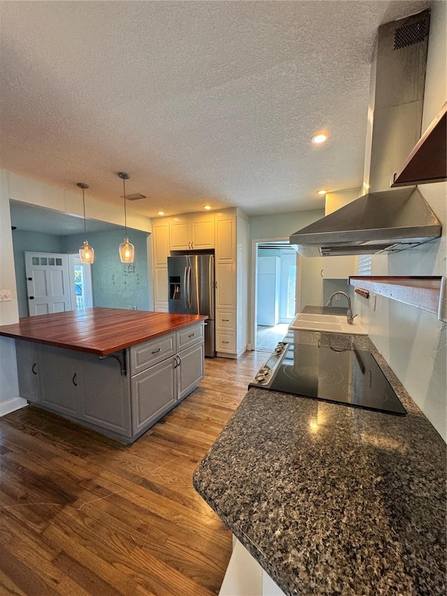 kitchen with wooden counters, a sink, island range hood, wood finished floors, and stainless steel fridge with ice dispenser