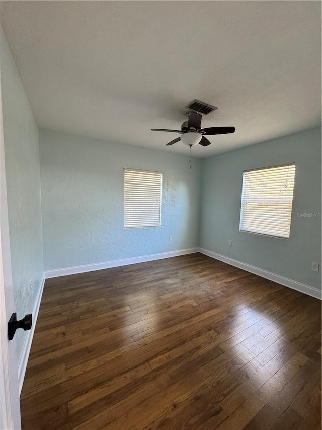 spare room with visible vents, dark wood finished floors, baseboards, and ceiling fan