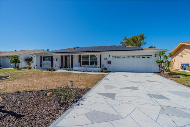 single story home featuring a garage, driveway, roof mounted solar panels, a front lawn, and stucco siding