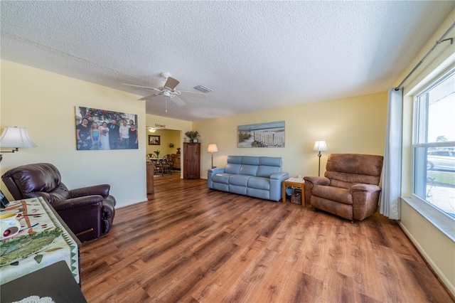 living area with visible vents, ceiling fan, a textured ceiling, and wood finished floors