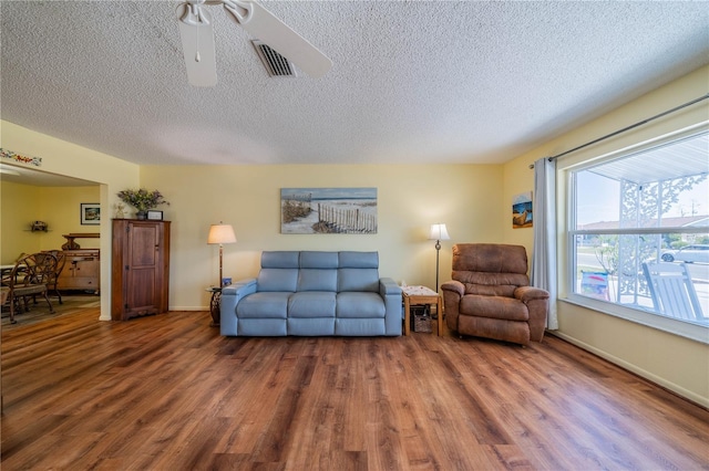 living area with visible vents, a textured ceiling, and wood finished floors