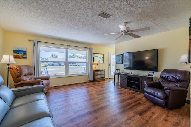 living room with a ceiling fan, visible vents, a textured ceiling, and wood finished floors