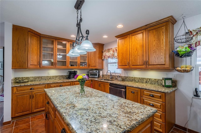 kitchen featuring brown cabinets, a sink, dark tile patterned floors, and stainless steel dishwasher