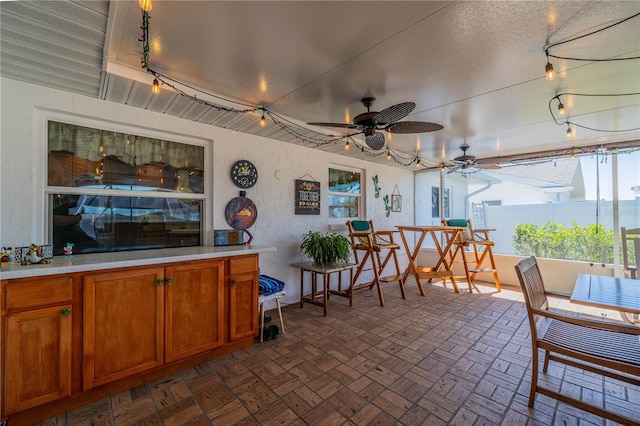 sunroom / solarium featuring rail lighting and ceiling fan