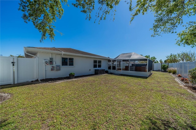 rear view of house featuring a sunroom, a yard, a fenced backyard, and a gate