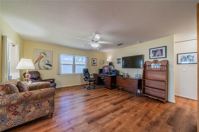 office featuring a ceiling fan, a textured ceiling, visible vents, and wood finished floors