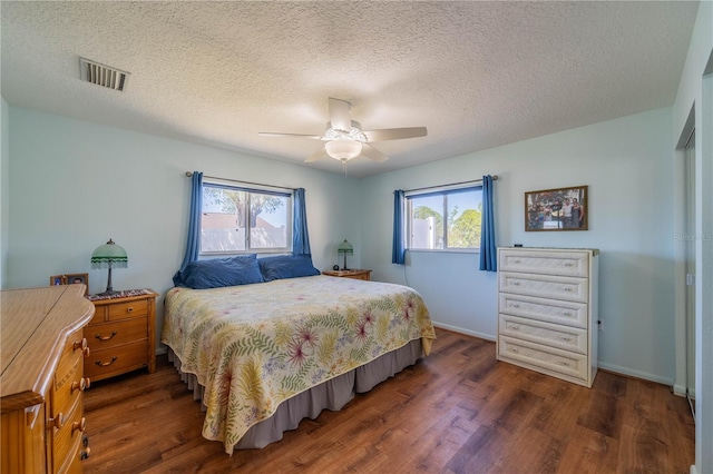 bedroom with visible vents, a ceiling fan, a textured ceiling, wood finished floors, and baseboards