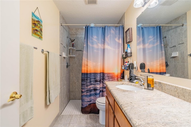 bathroom with a textured ceiling, tile patterned flooring, toilet, vanity, and tiled shower