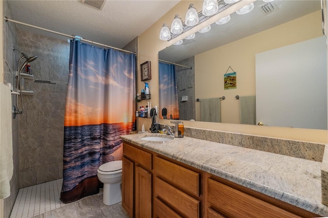 bathroom with toilet, visible vents, a tile shower, and vanity