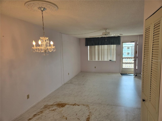 spare room featuring ceiling fan with notable chandelier and a textured ceiling