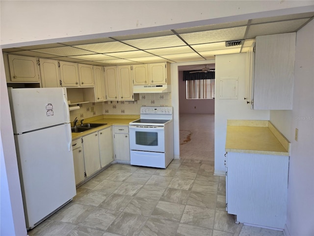 kitchen featuring white appliances, a sink, decorative backsplash, light countertops, and under cabinet range hood