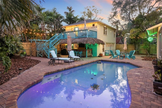 view of pool with fence, stairs, outdoor dry bar, a fenced in pool, and a patio area