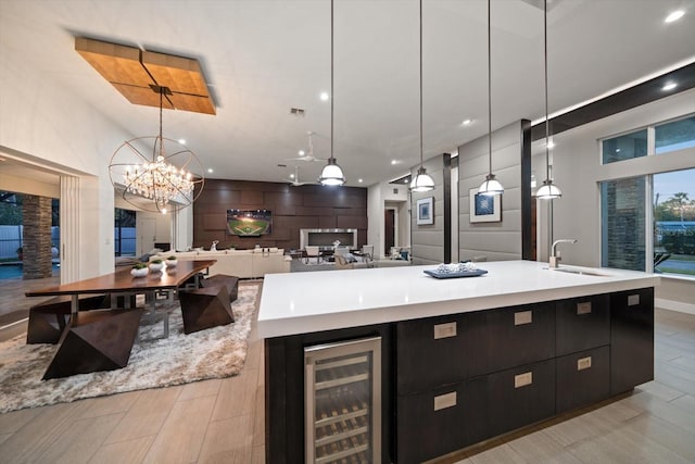 kitchen featuring light countertops, beverage cooler, a large island with sink, and a sink