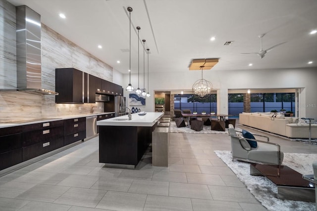 kitchen with visible vents, a sink, open floor plan, wall chimney exhaust hood, and light countertops