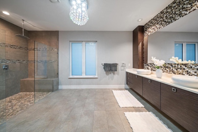 bathroom featuring backsplash, baseboards, walk in shower, and a sink