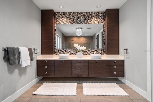 bathroom with double vanity, baseboards, a tile shower, and a sink