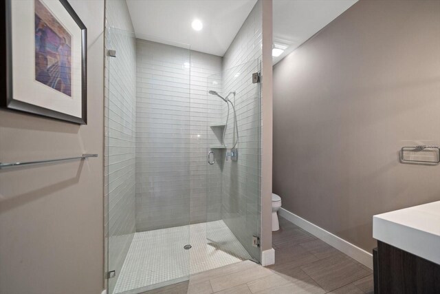 bathroom with vanity, a shower stall, toilet, and baseboards