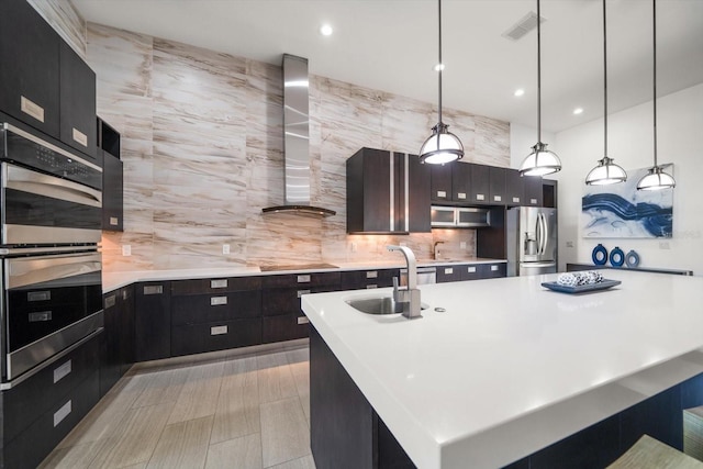 kitchen with visible vents, light countertops, stainless steel appliances, wall chimney exhaust hood, and a sink