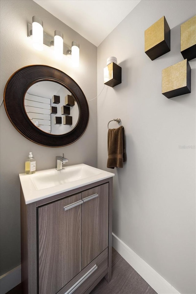 bathroom with vanity, wood finished floors, and baseboards