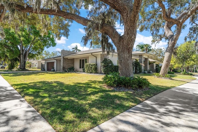 view of front facade featuring stucco siding, an attached garage, and a front yard