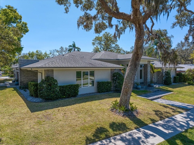 view of front of property with stucco siding, a front yard, and roof with shingles