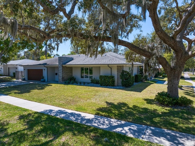 ranch-style house with stucco siding, concrete driveway, a front yard, and a garage