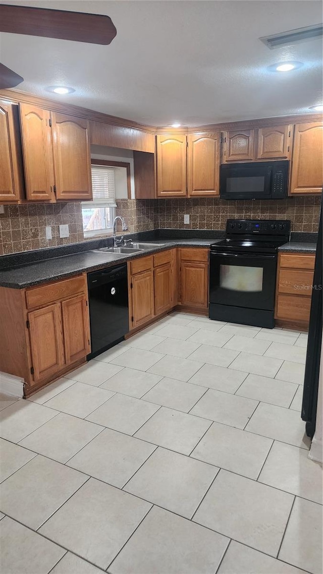 kitchen with a sink, decorative backsplash, black appliances, brown cabinetry, and dark countertops