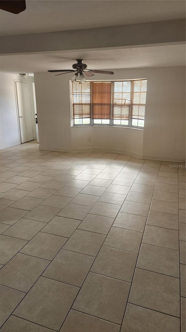 empty room featuring ceiling fan, baseboards, and light tile patterned floors