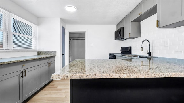 kitchen featuring black microwave, electric stove, a sink, and gray cabinets