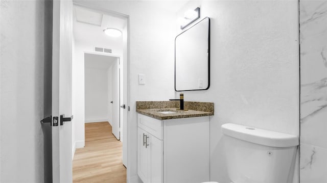 bathroom with toilet, visible vents, wood finished floors, and vanity