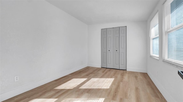 unfurnished bedroom with baseboards, a closet, and light wood-style floors