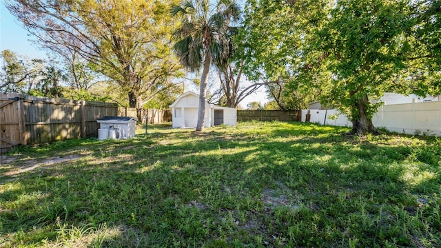 view of yard featuring a storage shed, a fenced backyard, and an outbuilding