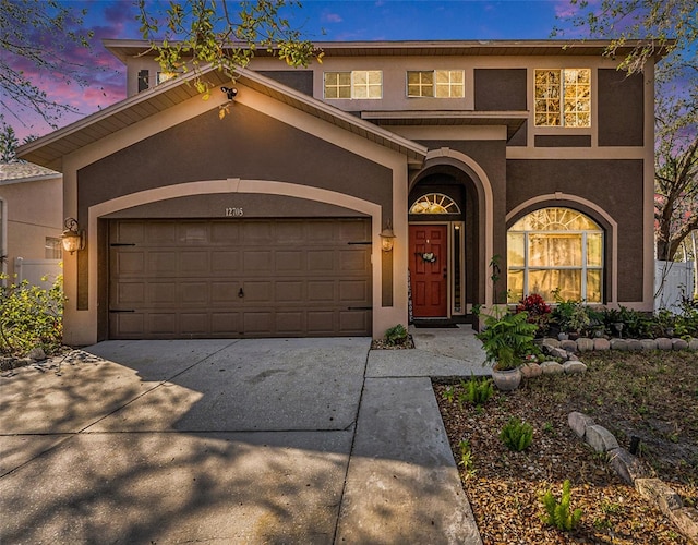 view of front facade with driveway, an attached garage, and stucco siding