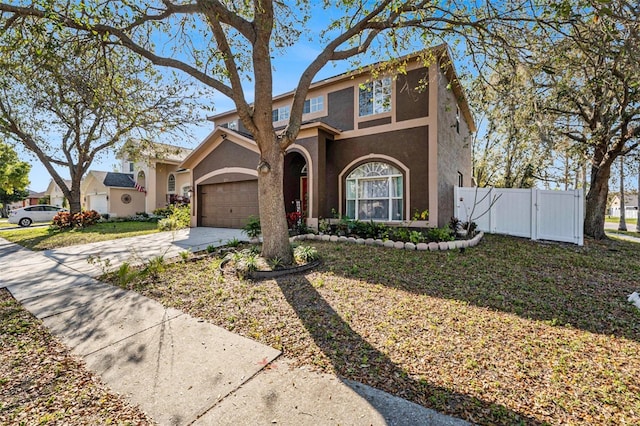 view of front of house featuring a garage, concrete driveway, a gate, fence, and stucco siding