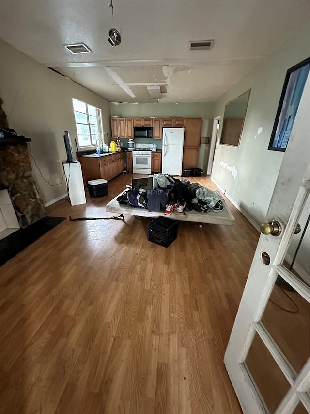 kitchen with white appliances, visible vents, brown cabinets, and wood finished floors