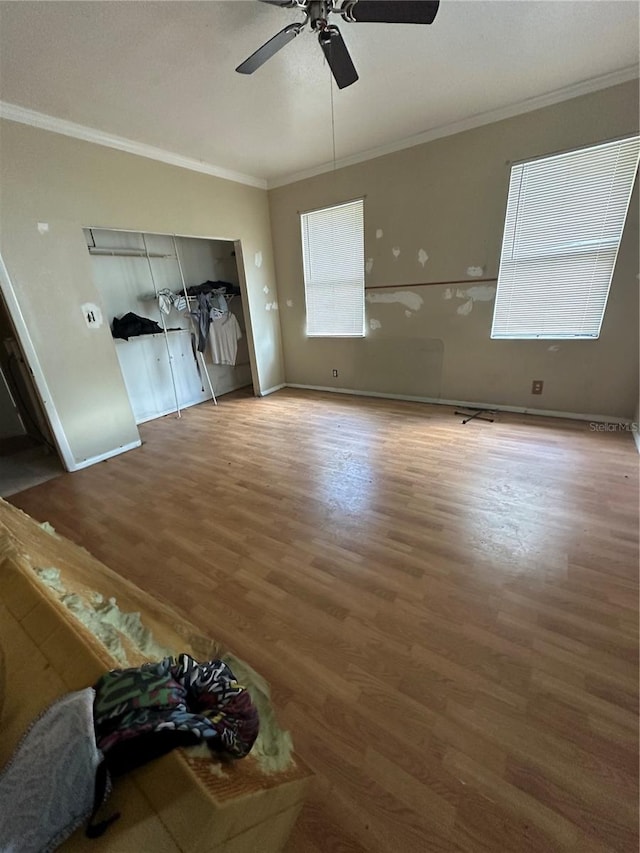 unfurnished living room with ceiling fan, crown molding, baseboards, and wood finished floors