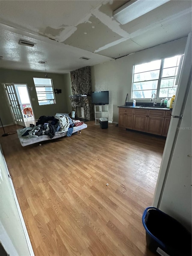 living area featuring light wood-style floors, visible vents, plenty of natural light, and a fireplace