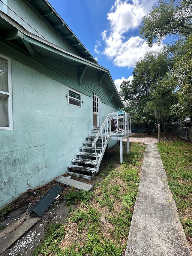 view of side of property featuring a wooden deck, fence, and stucco siding