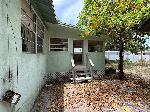 view of home's exterior featuring entry steps, fence, and stucco siding