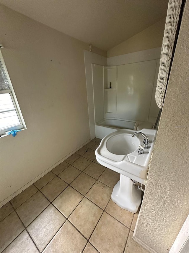 full bath with vaulted ceiling, tub / shower combination, a sink, and tile patterned floors