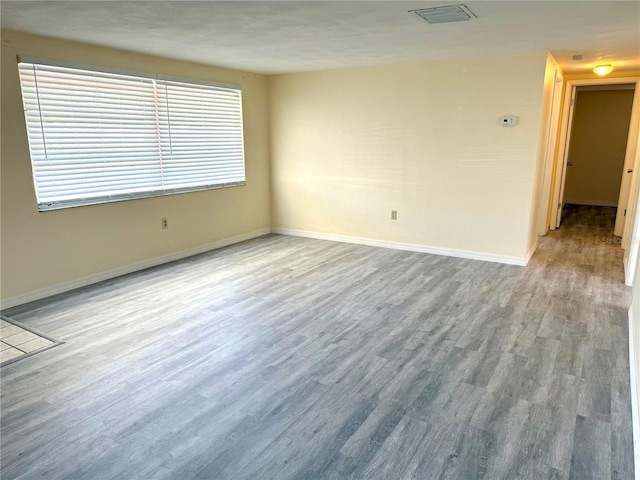 spare room with baseboards, visible vents, and wood finished floors